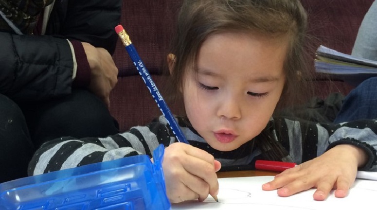 A little girl holding a pencil and drawing