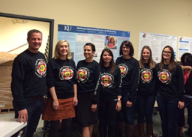 CRELI staff and scholars wearing uniforms and standing before a wall with multiple posters